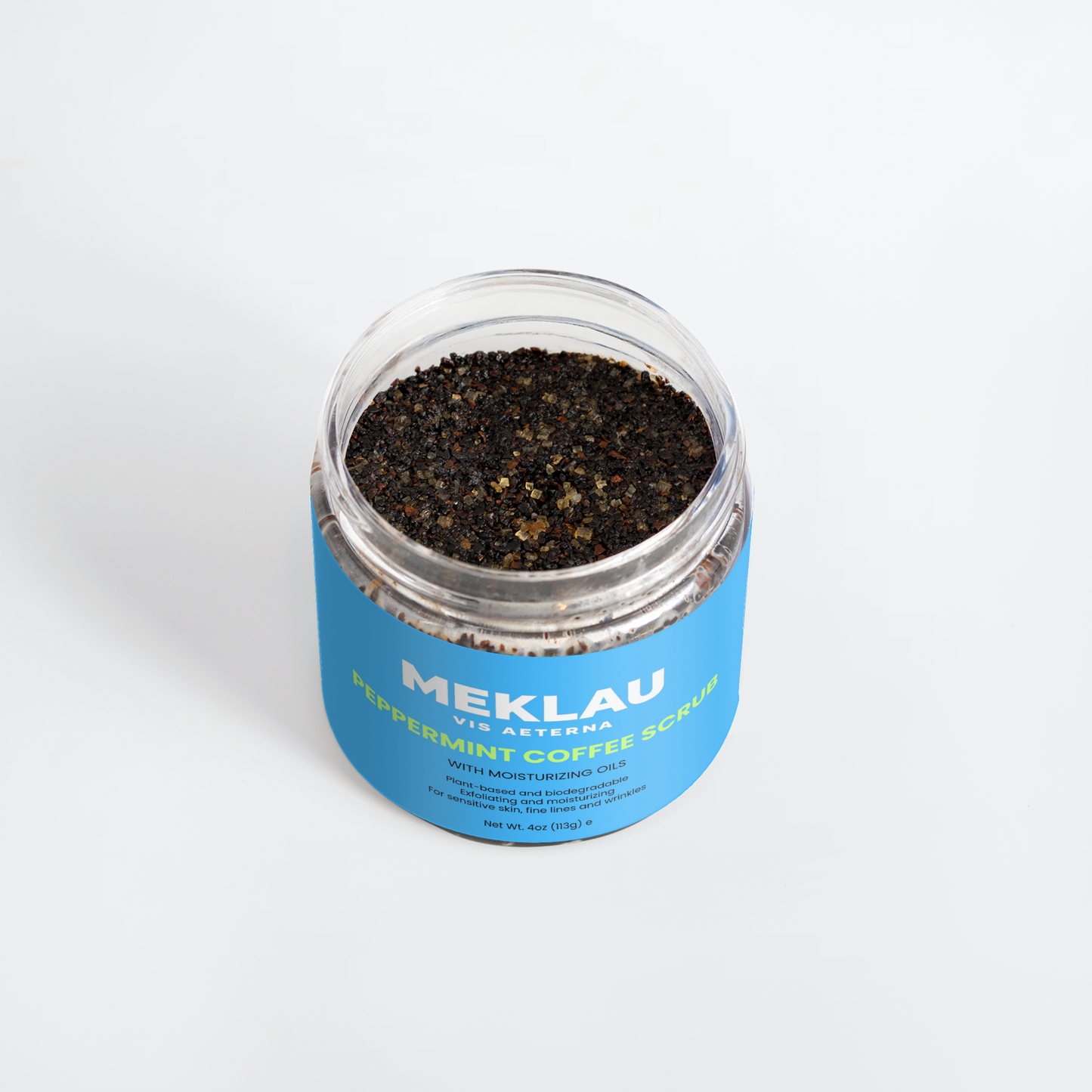 A clear plastic jar of Meklau Peppermint Coffee Scrub with a bright blue label, filled with dark coffee scrub, on a clean white background.