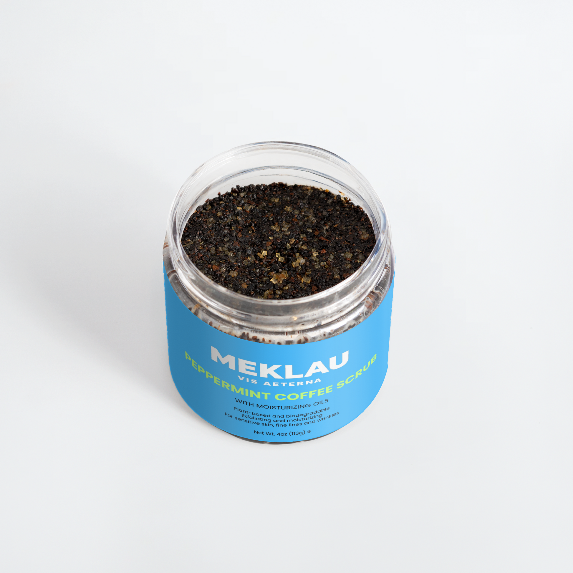 A clear plastic jar of Meklau Peppermint Coffee Scrub with a bright blue label, filled with dark coffee scrub, on a clean white background.